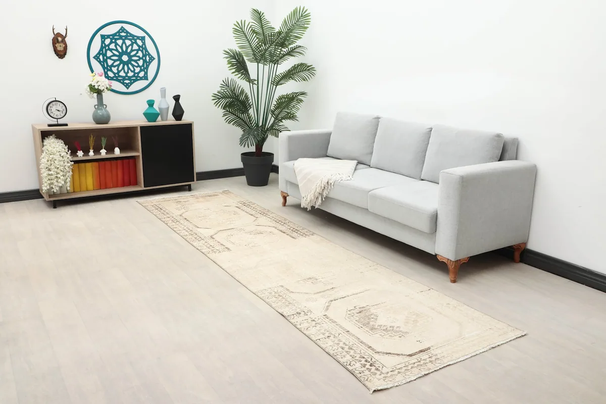 Long view of the beige runner rug extending across a room with a sofa and decor