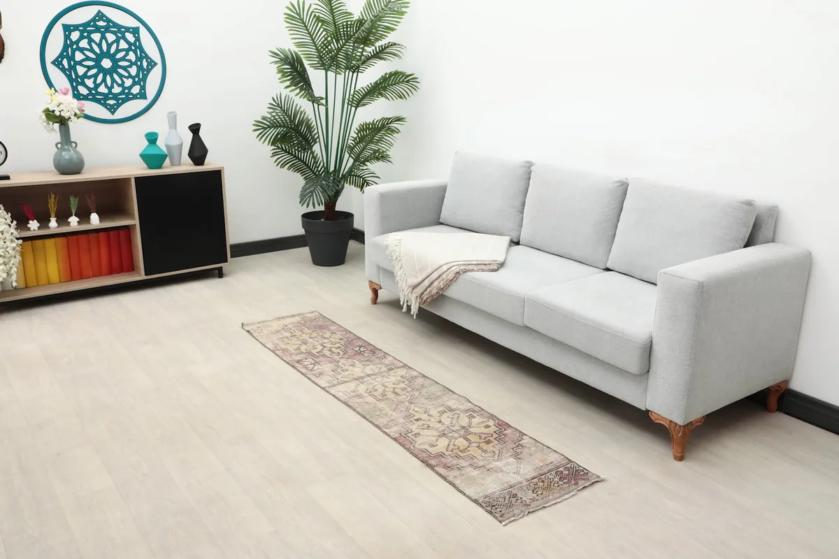 Runner rug in a living room setting next to a gray sofa and wooden cabinet