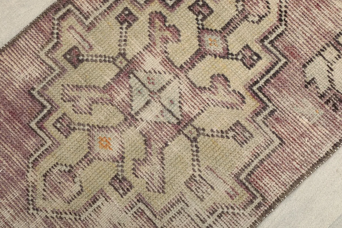 Detailed view of the central geometric motif in rose, beige, and gray tones