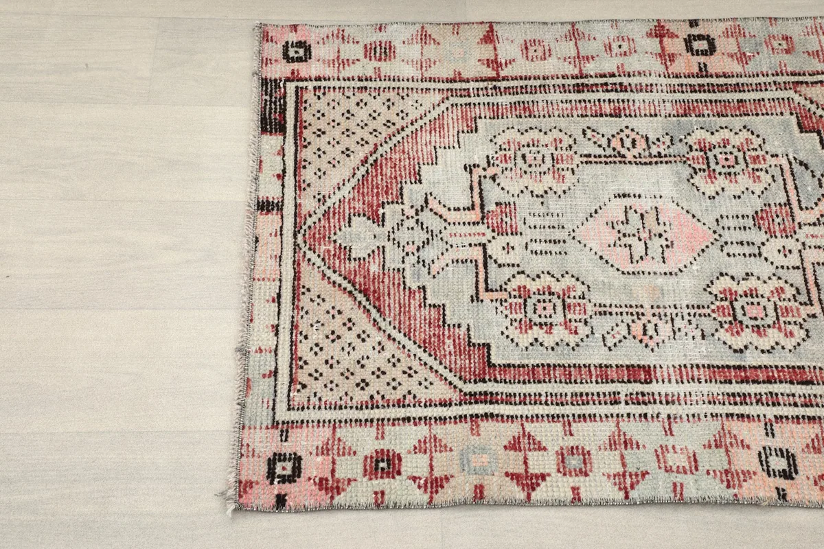 Close-up of the top left corner of the rug, showing the faded gray and rose colors.