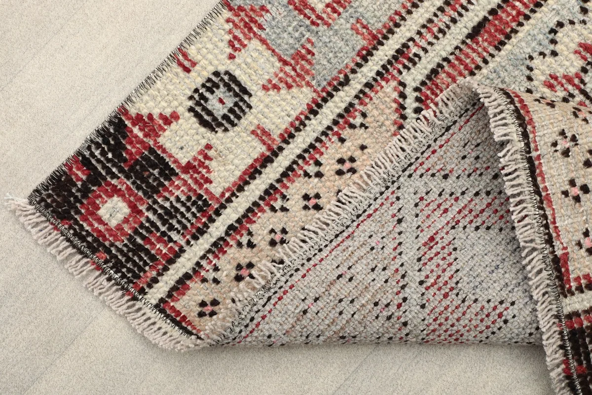 View showing the back of the rug where it is folded, revealing the cotton foundation.