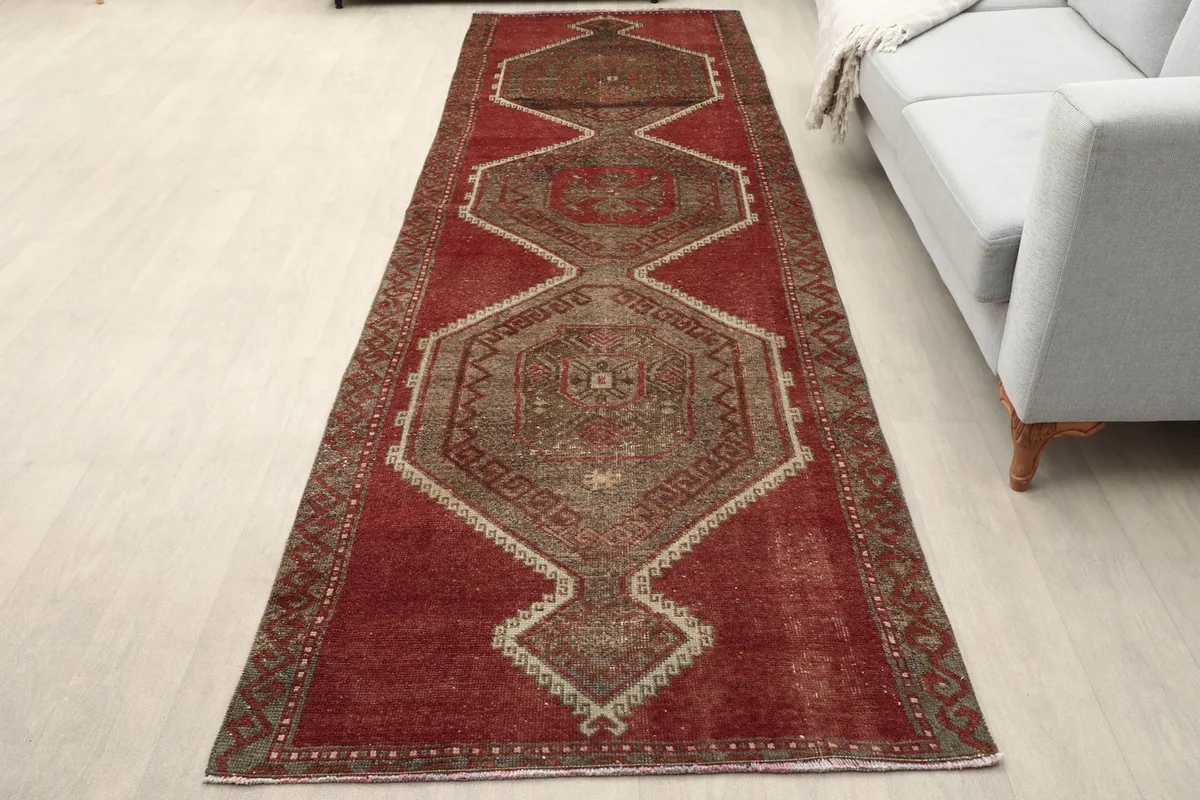 Vintage red runner rug placed in a living room setting next to a sofa