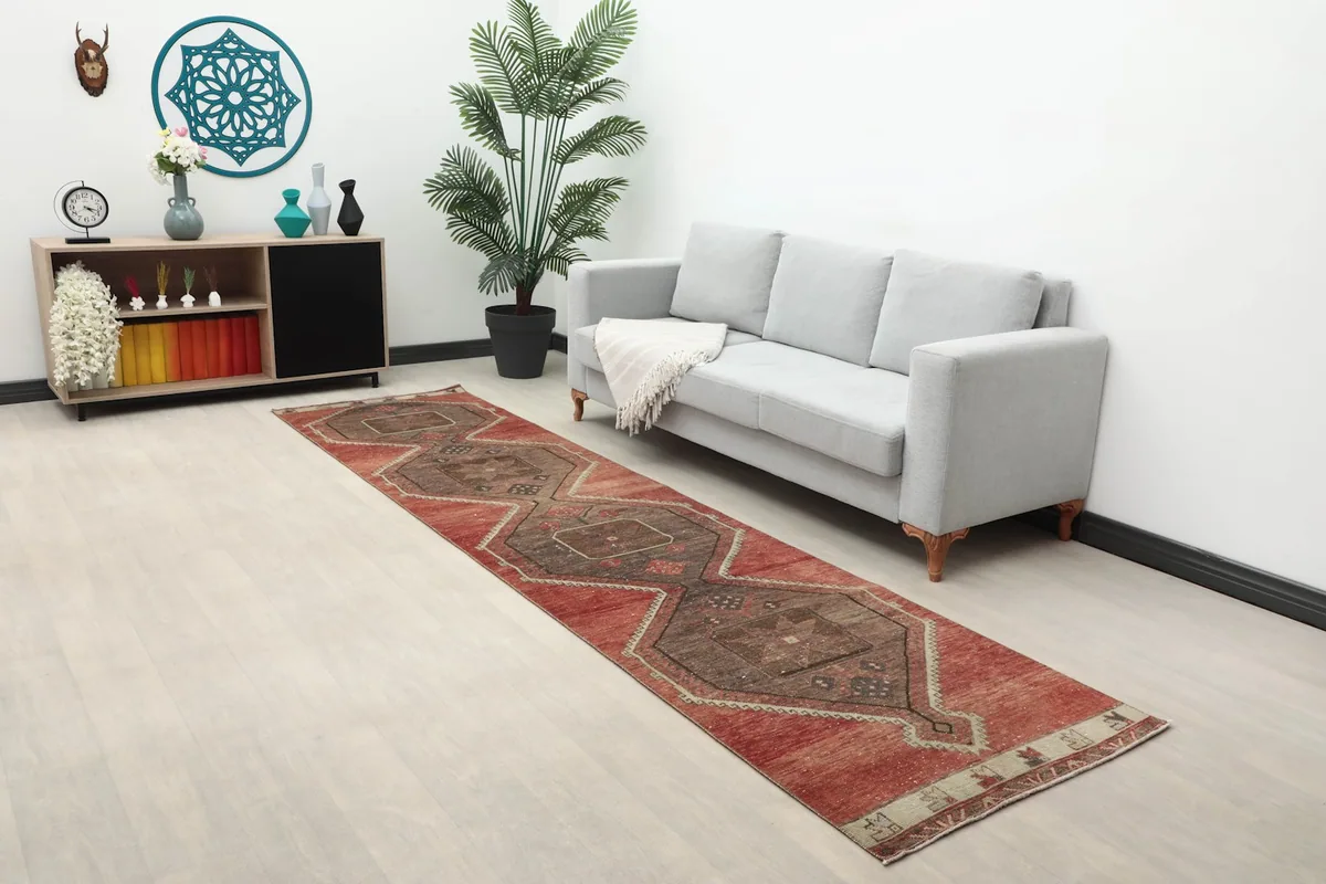 Long view of the rust and brown runner rug in a room with a gray sofa and plants