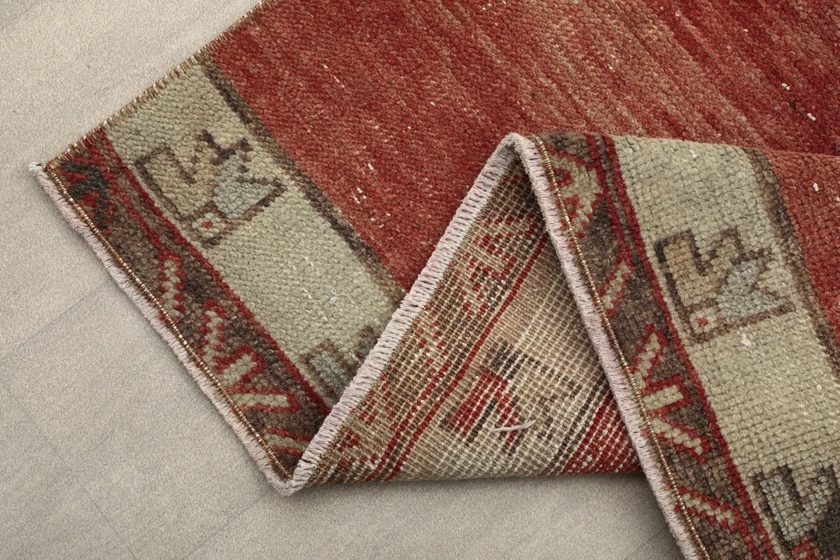 Folded edge of the runner rug, revealing the back and the beige border pattern