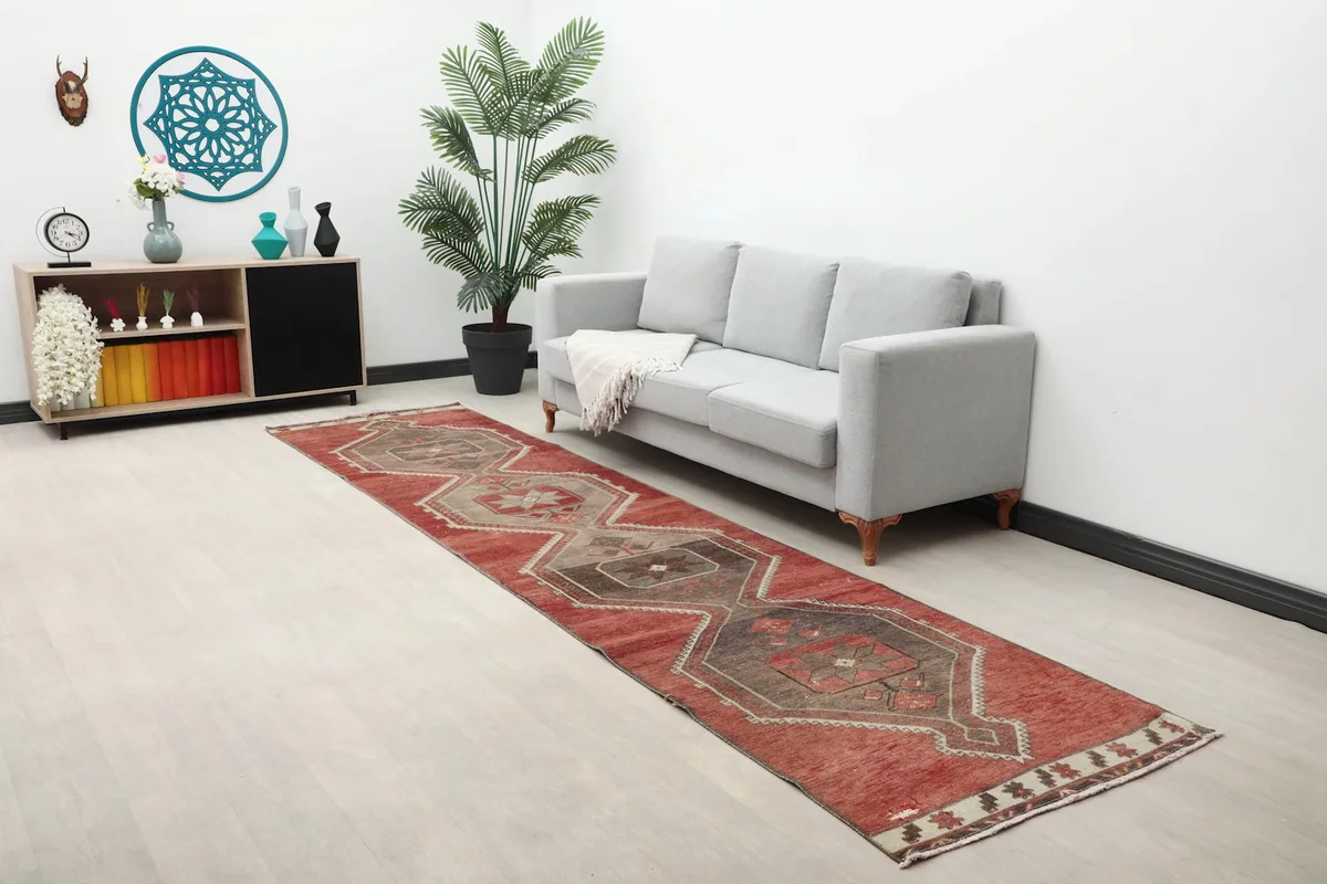 Runner rug displayed in a room setting next to a gray sofa, highlighting its long dimensions.