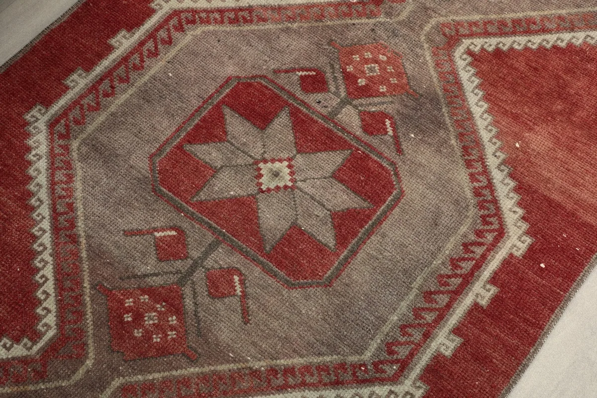 Close-up of a central gray geometric motif with a red star and subtle beige details in the runner.