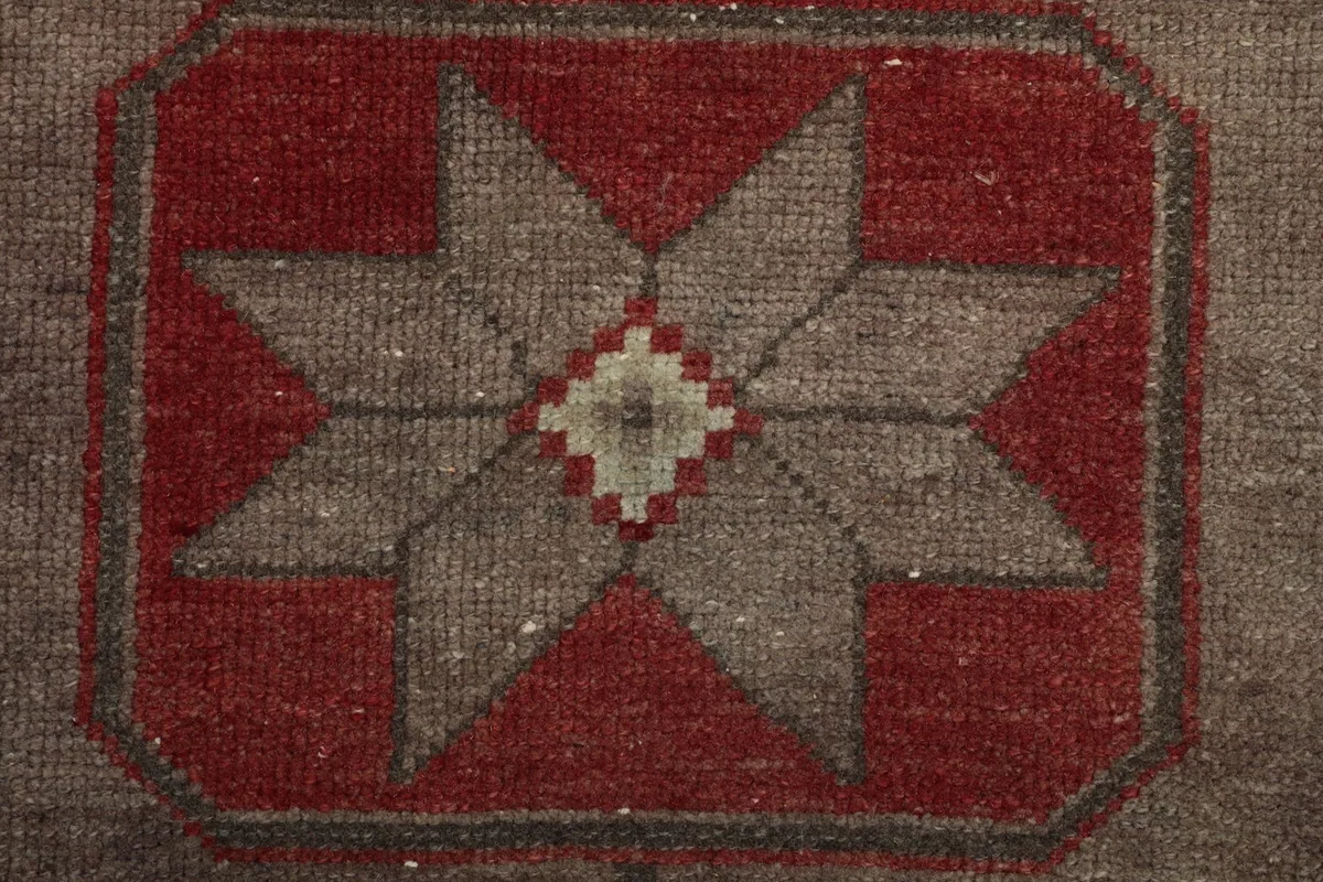 Detailed shot of a single star motif within a geometric shape, showing the red and gray wool pile.