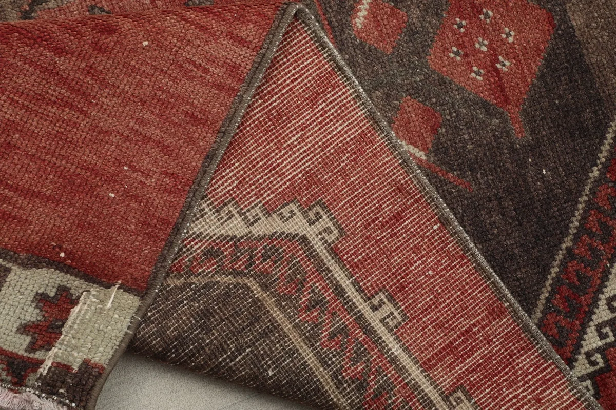 Underside view of the hand-knotted cotton foundation and the red wool pile of the vintage runner rug.