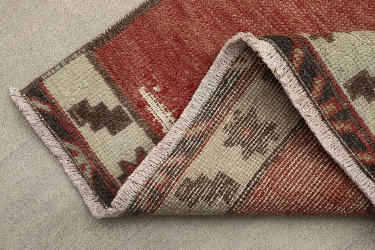 View of the rug's edge, showing the beige and brown patterned border and the short, natural fringes.