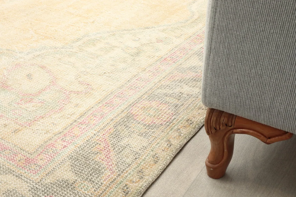 Detail of the rug's border next to a furniture leg, emphasizing the pattern and scale