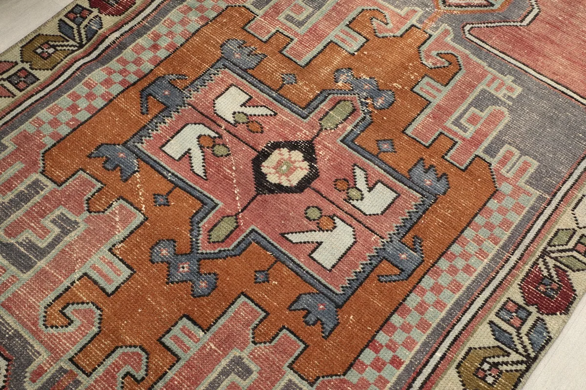 Close-up of the central medallion design, revealing the intricate motifs and faded rose, rust, gray tones