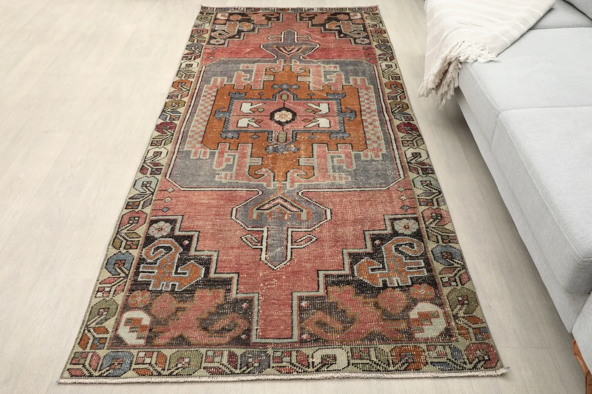 Overhead view of the rose tribal runner rug placed on a light floor next to a sofa