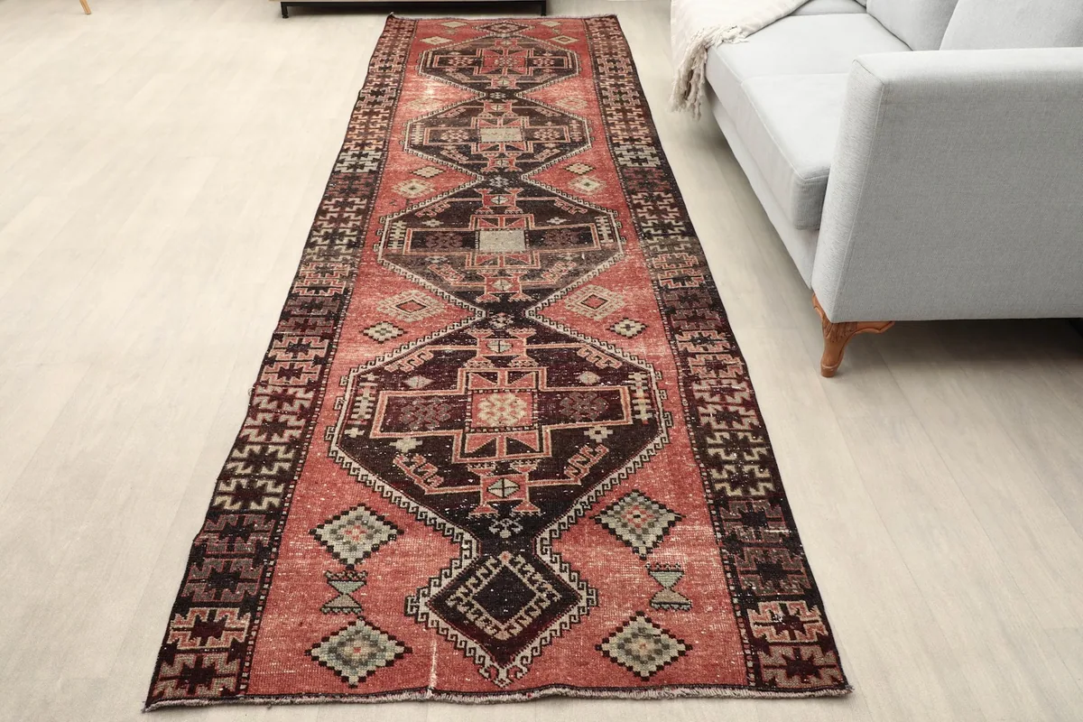 Vintage rust runner rug laid out in a modern hallway with a gray sofa