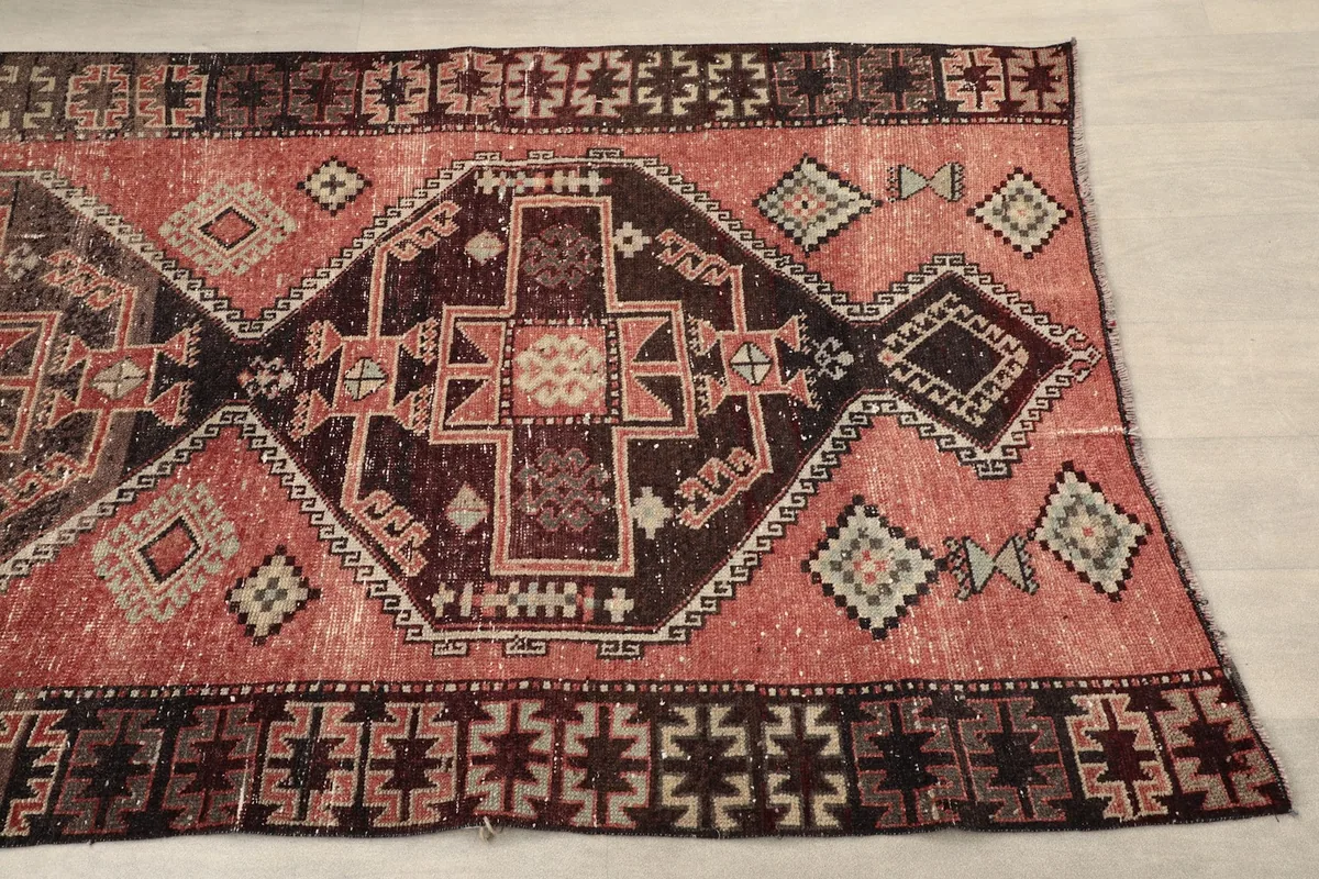 Close-up view of the rug's rust field and black geometric border with beige motifs
