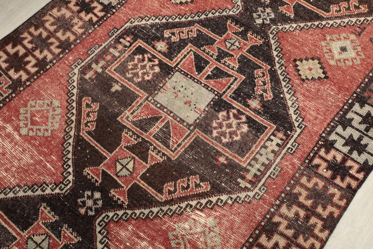 Close-up of the rug's texture and intricate geometric patterns in rust, black, and beige