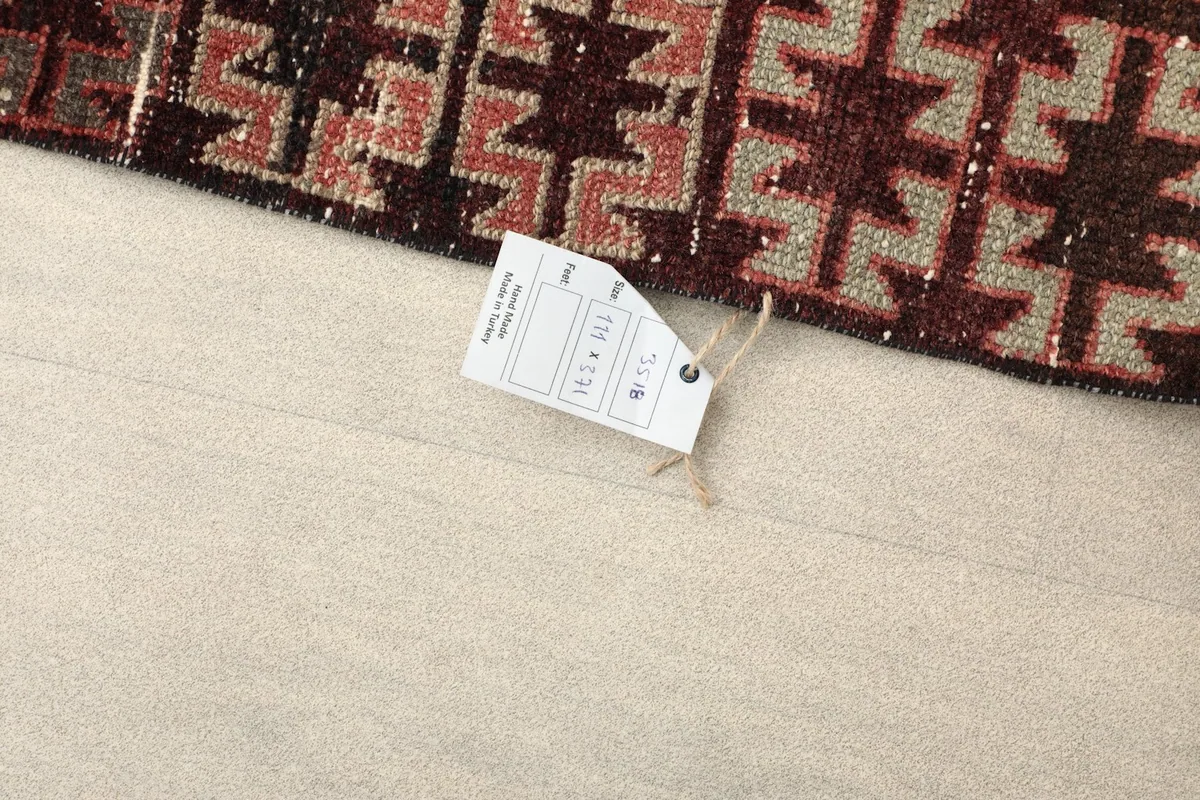Tag showing the rug's dimensions in centimeters and inches on a light floor