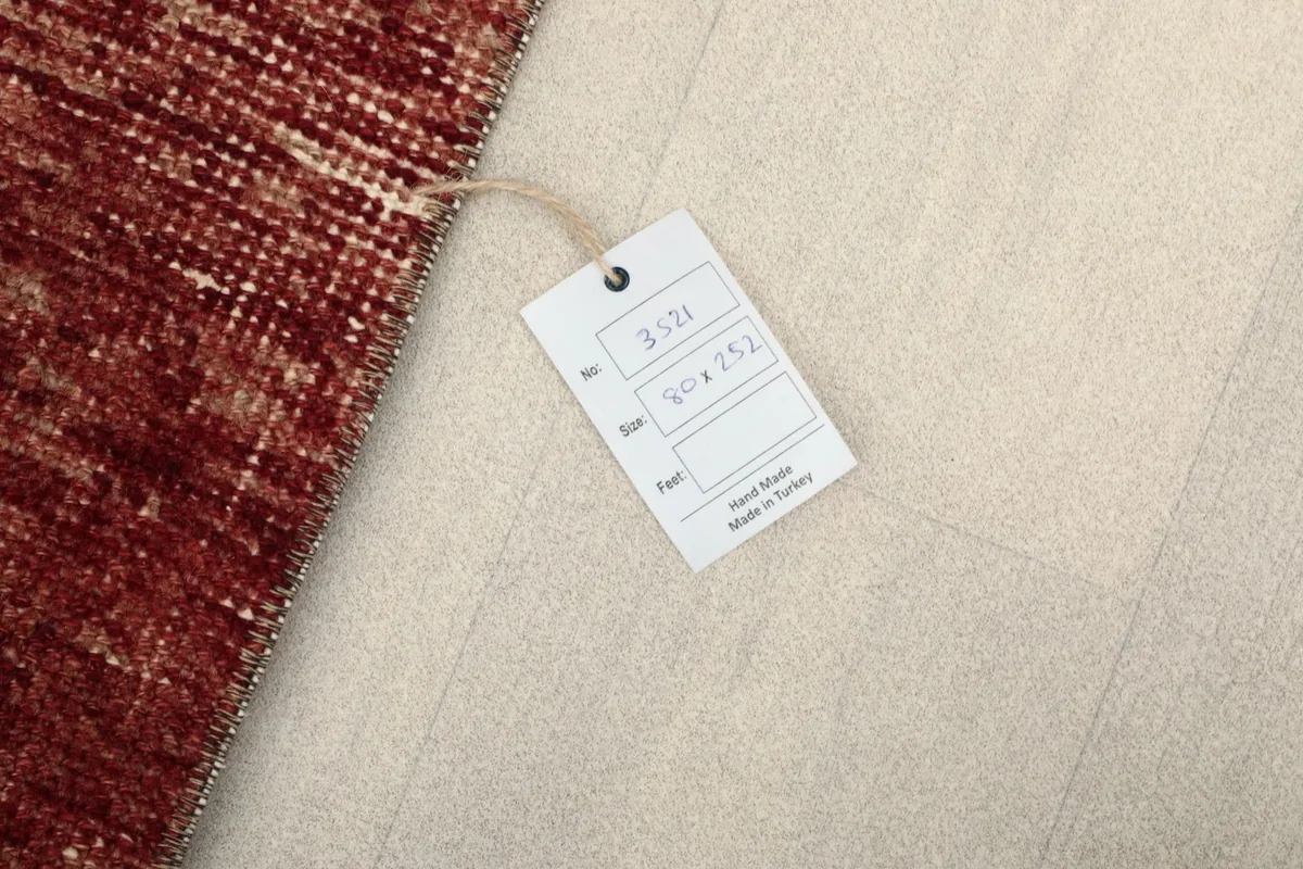 Tag showing the rug's dimensions 80 x 252 cm and origin, placed on the floor next to the rug