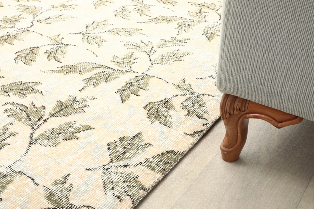 Close-up of the rug next to a wooden furniture leg, showing the subtle tones and pattern in a home setting