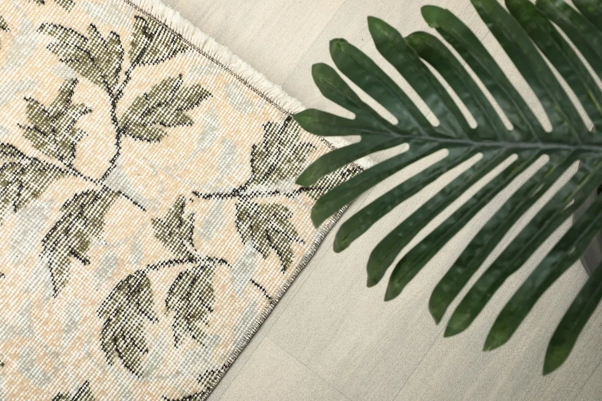 Close-up of the rug's pattern with a green plant leaf for scale and texture comparison