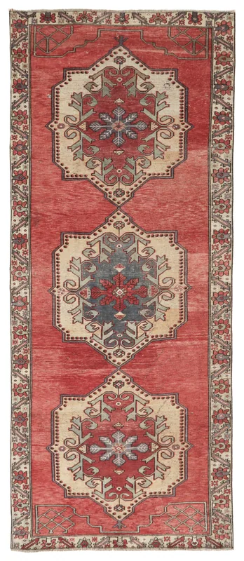 Full top view of the vintage Anatolian runner rug with red field and geometric medallions on a white background.