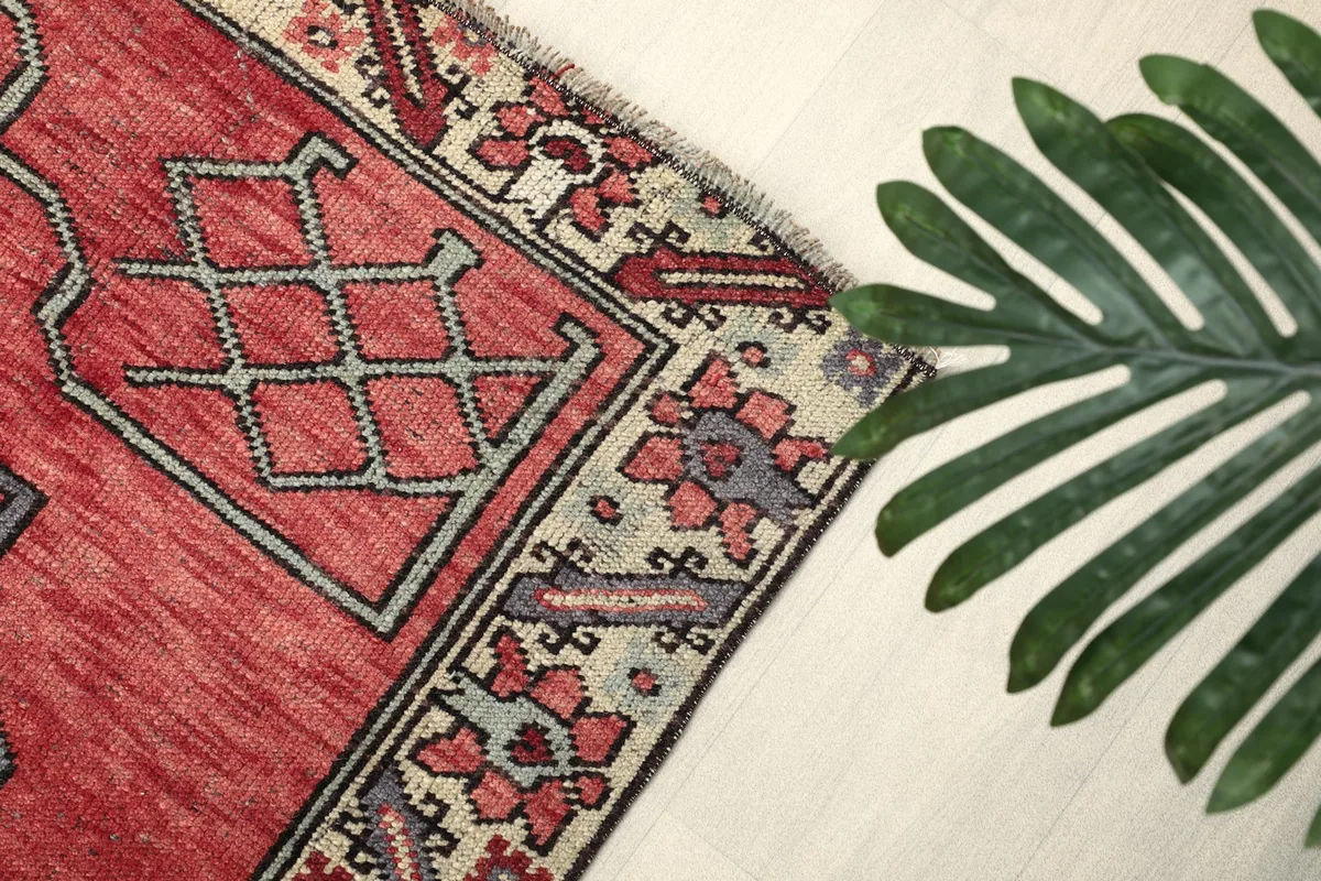 Angled view of the rug's edge and border, with a green leaf for scale and texture comparison.