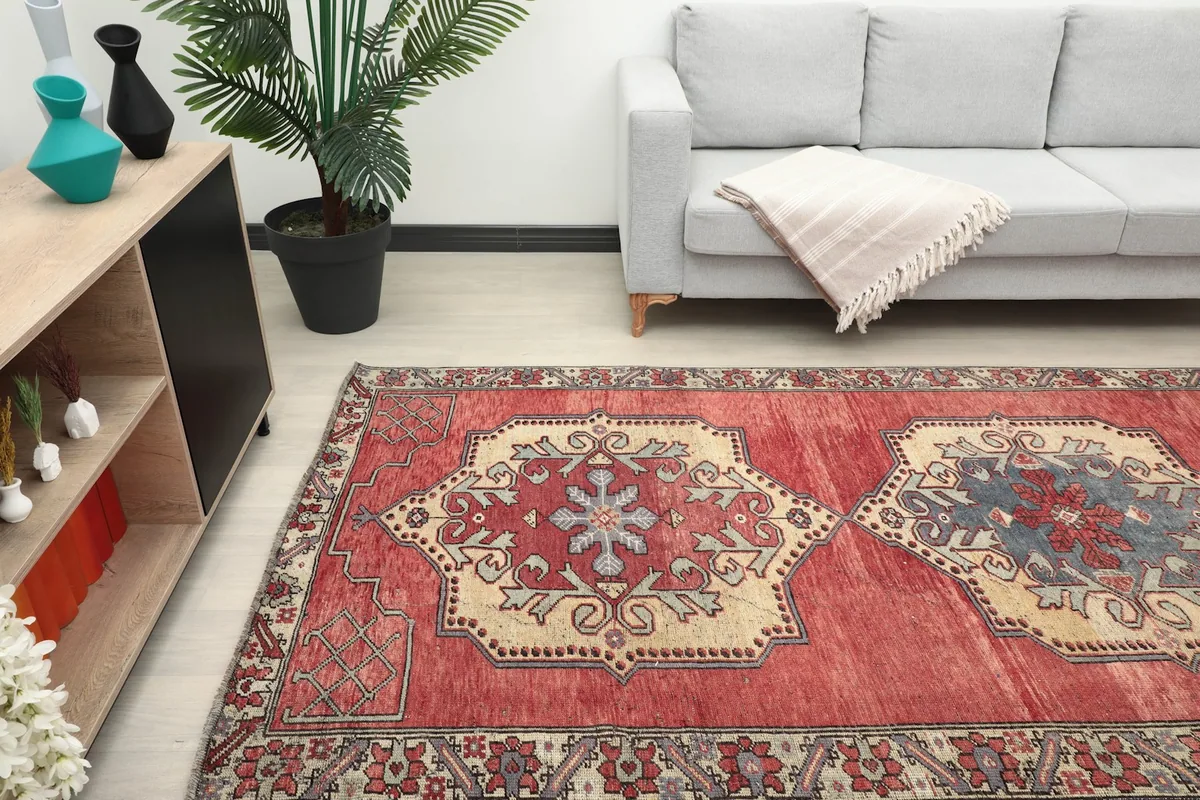 Close-up view of the rug within a room, focusing on the central medallions and the red field's color variation.