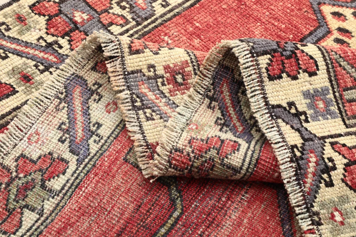 Close-up of the rug's low wool pile and the intricate weaving of the border and field patterns.