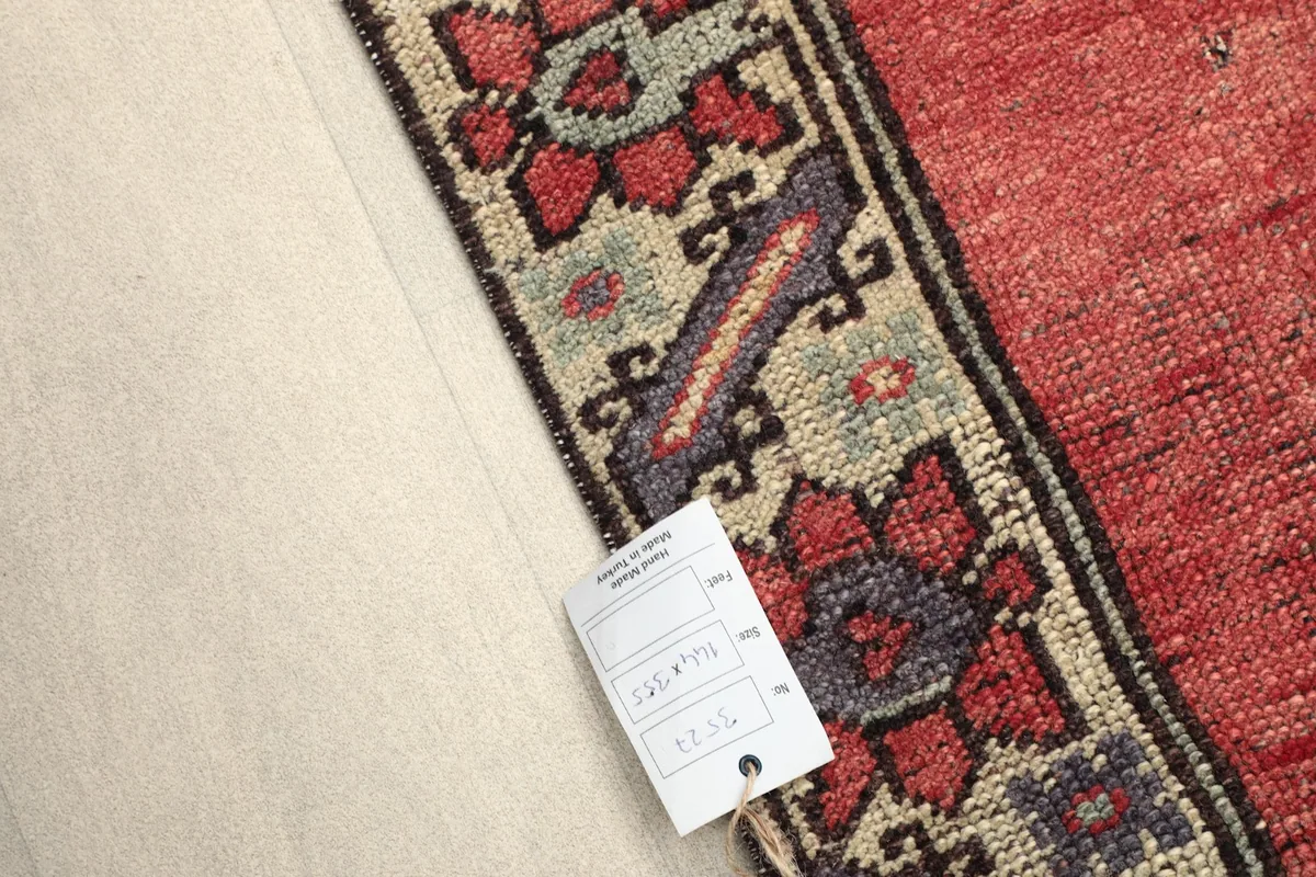 View of the rug's reverse side near the border with a product tag, showing the hand-knotted foundation.