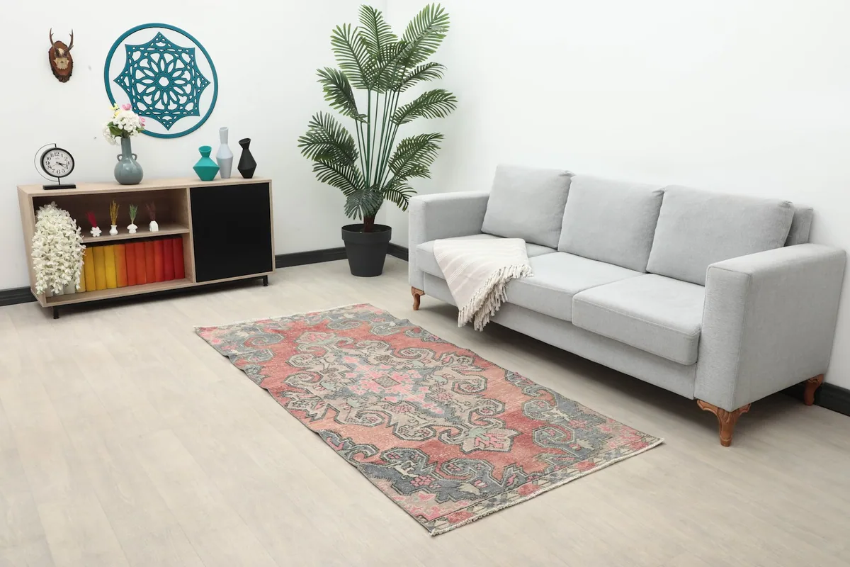 Wide shot of the rug in a living room next to a gray sofa and wooden cabinet