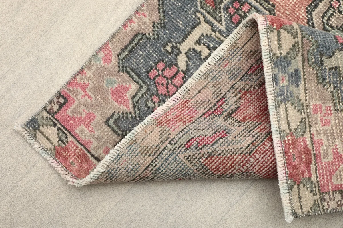 Corner of the rug folded to show the wool pile and cotton foundation construction