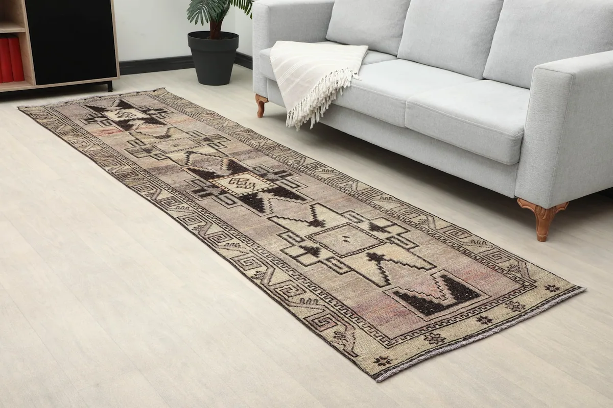 Angled view of the runner in a room, emphasizing the muted rose and beige tones and tribal motifs.