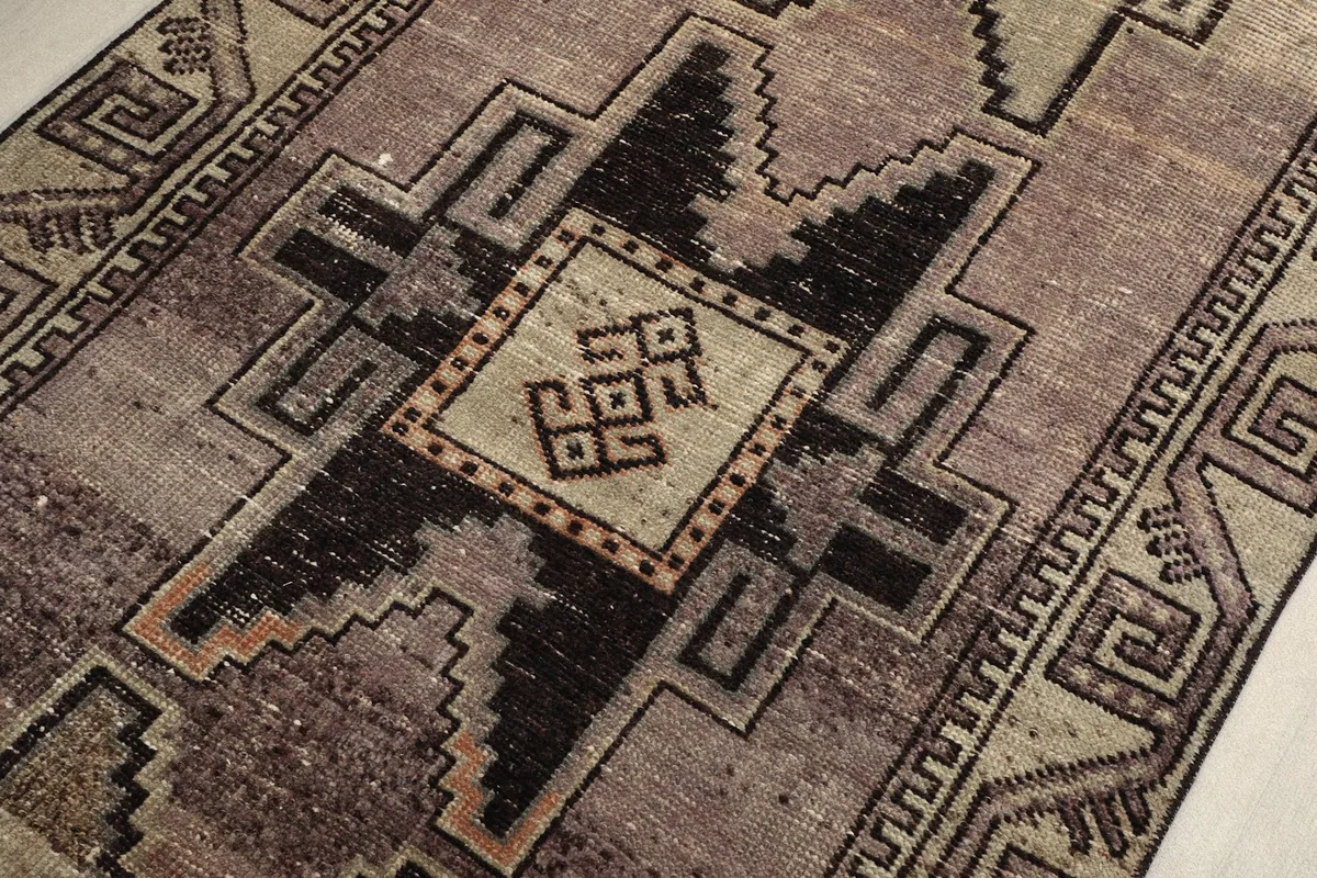 Detailed view of the rug's surface, highlighting the charcoal motifs and the subtle color shifts in the rose field.