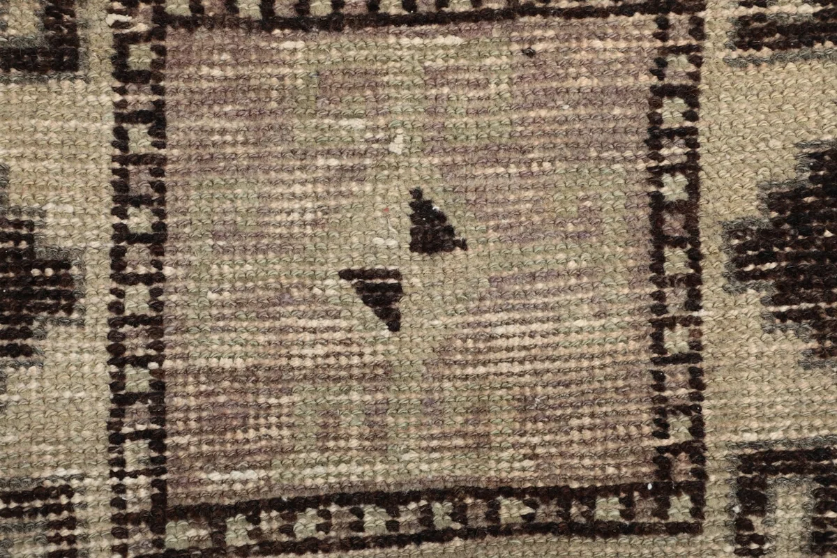 Close-up of the low wool pile, showing texture and color variation within a central motif.