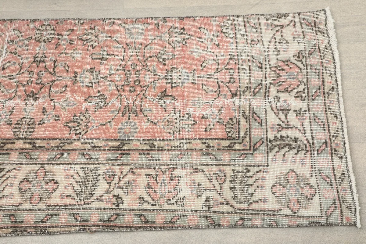 Close-up view of the rug's pattern, showing the rose field and the intricate gray and ivory floral border.