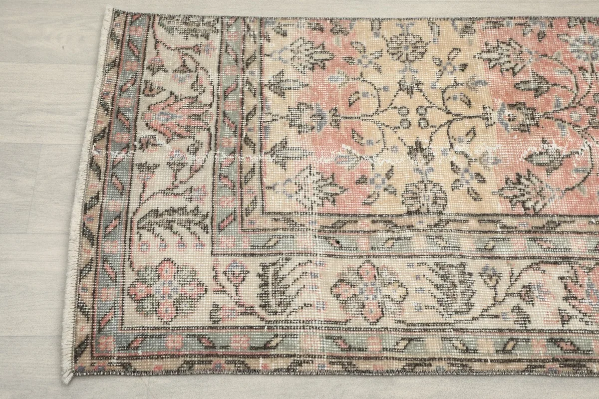 Detailed section of the rug, focusing on the blend of rose, gray, and ivory colors in the botanical motifs.
