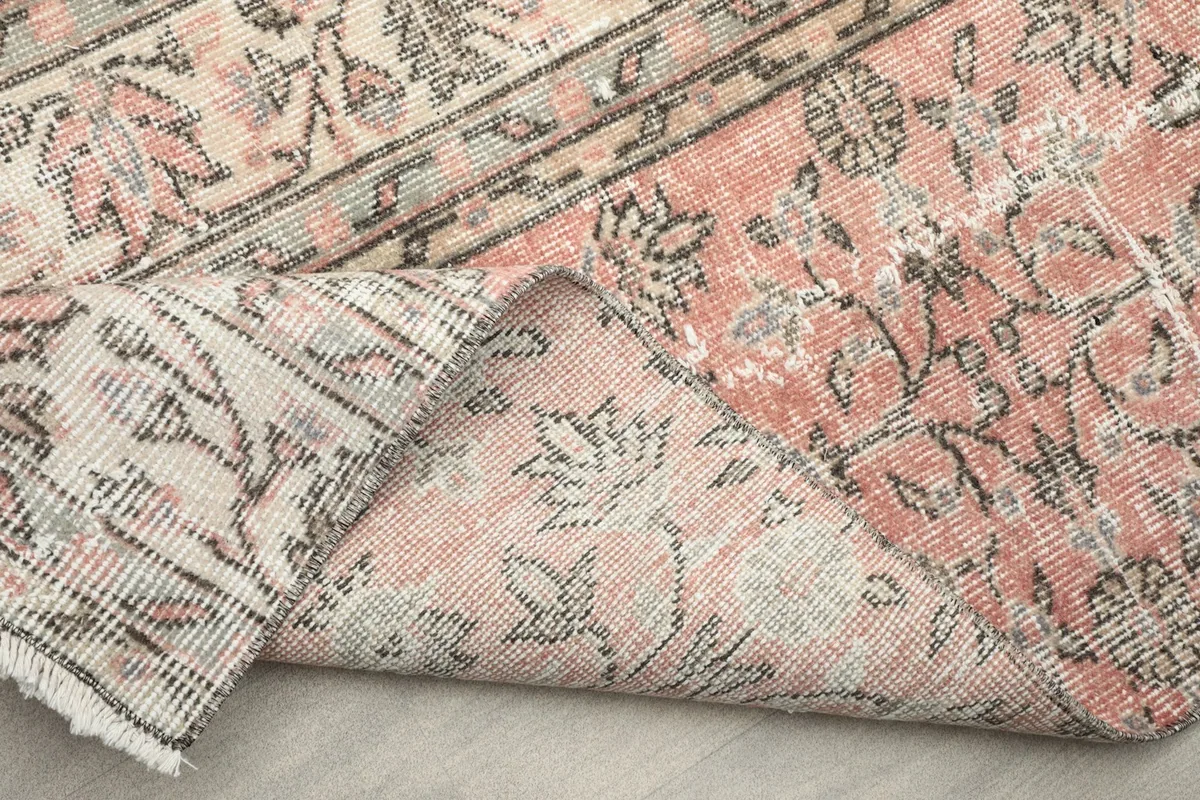 Corner of the rug folded back to show the cotton foundation and the reverse side of the hand-knotting.