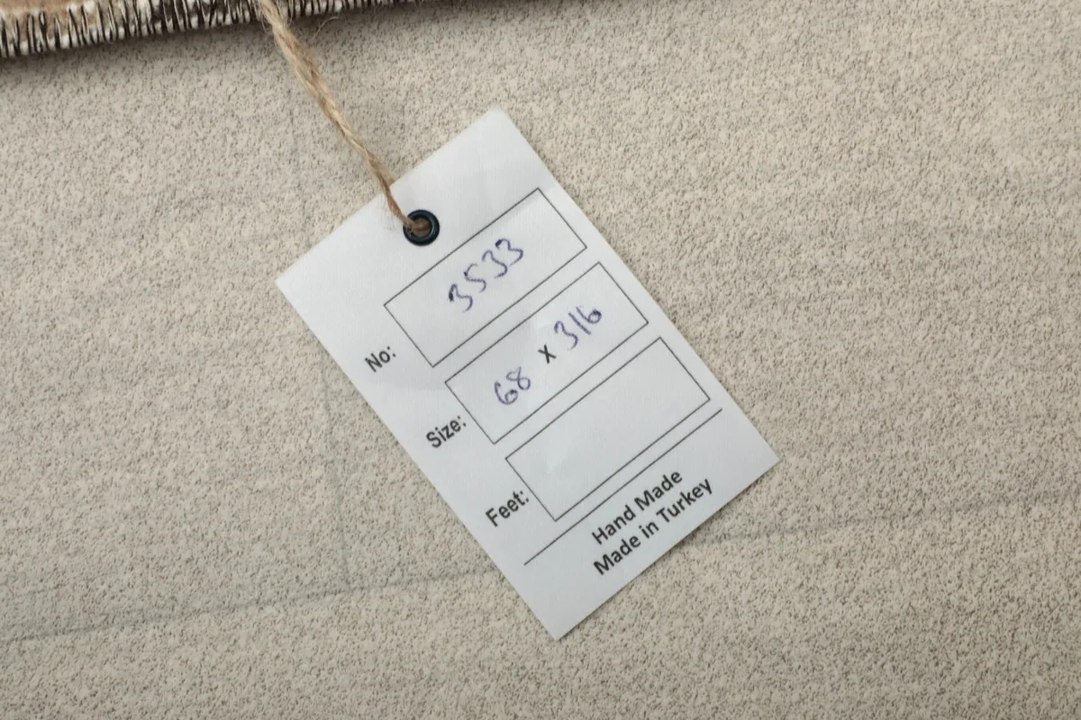 Product tag attached to the rug, displaying the item number and size in centimeters, confirming handmade origin.