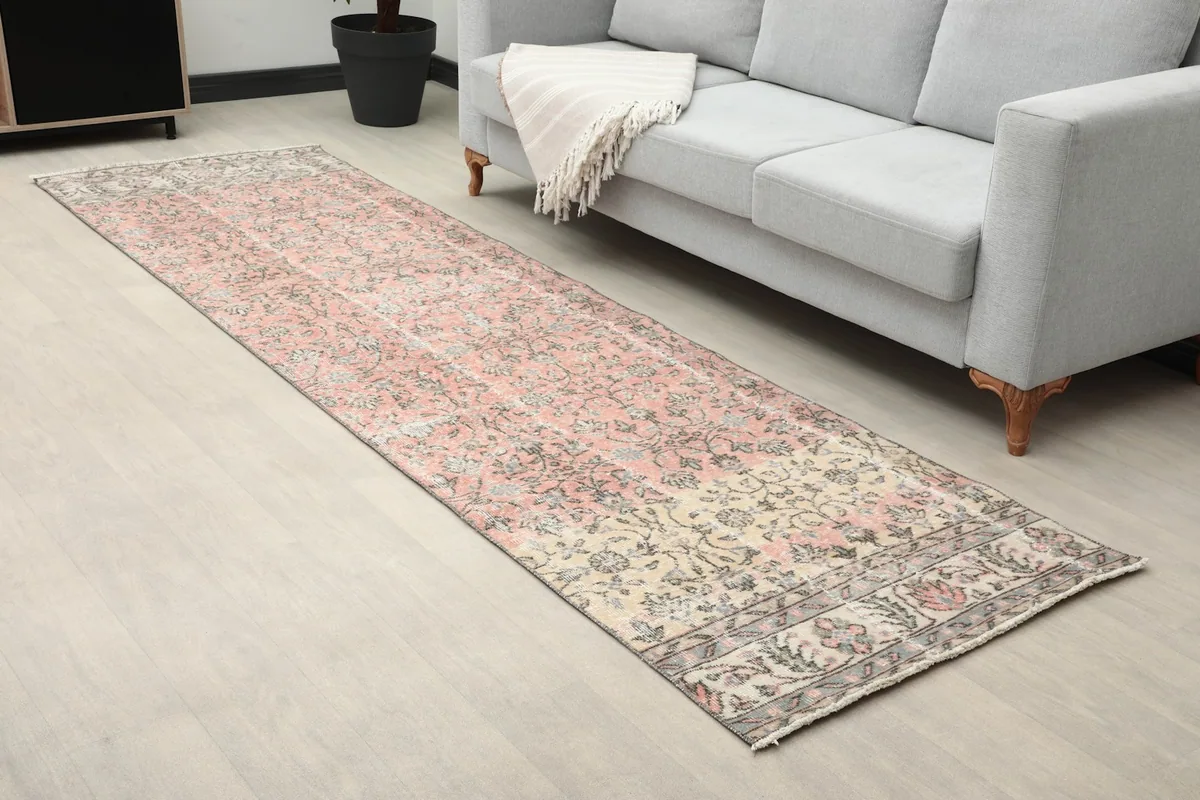 Close-up angled view of the runner rug, highlighting the pink and beige floral patterns