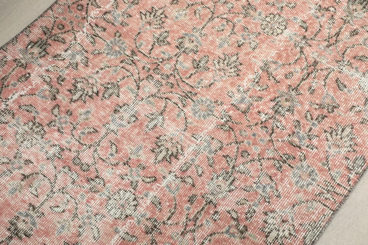 Macro view of the pink field with faded gray and beige floral patterns, showing texture