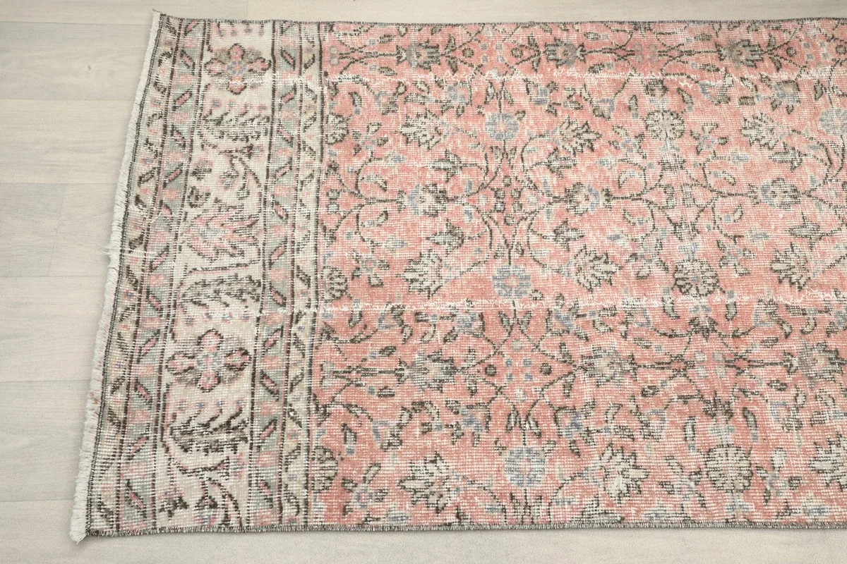 Close-up of the rug's border design and the end with fringes, showing the gray and beige tones