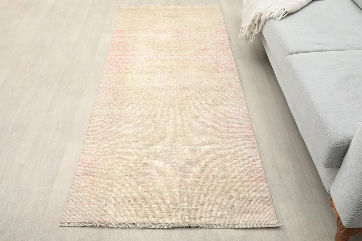 Overhead view of the cream and rose runner placed on a light floor next to a sofa
