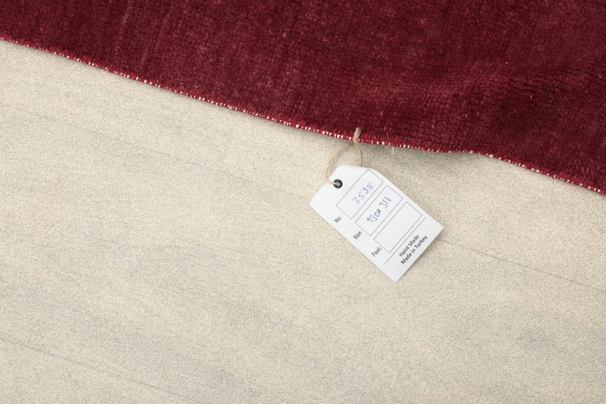 Product tag attached to the corner of the rose vintage rug, showing origin and details.