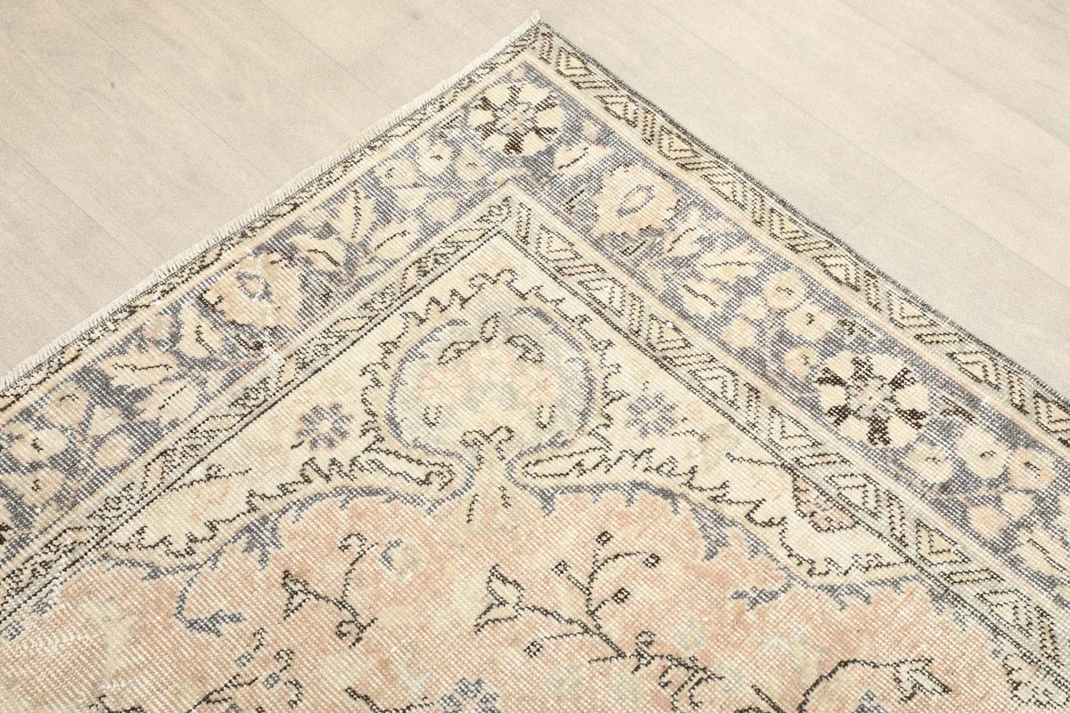 Corner detail showing the beige field and gray border with floral patterns