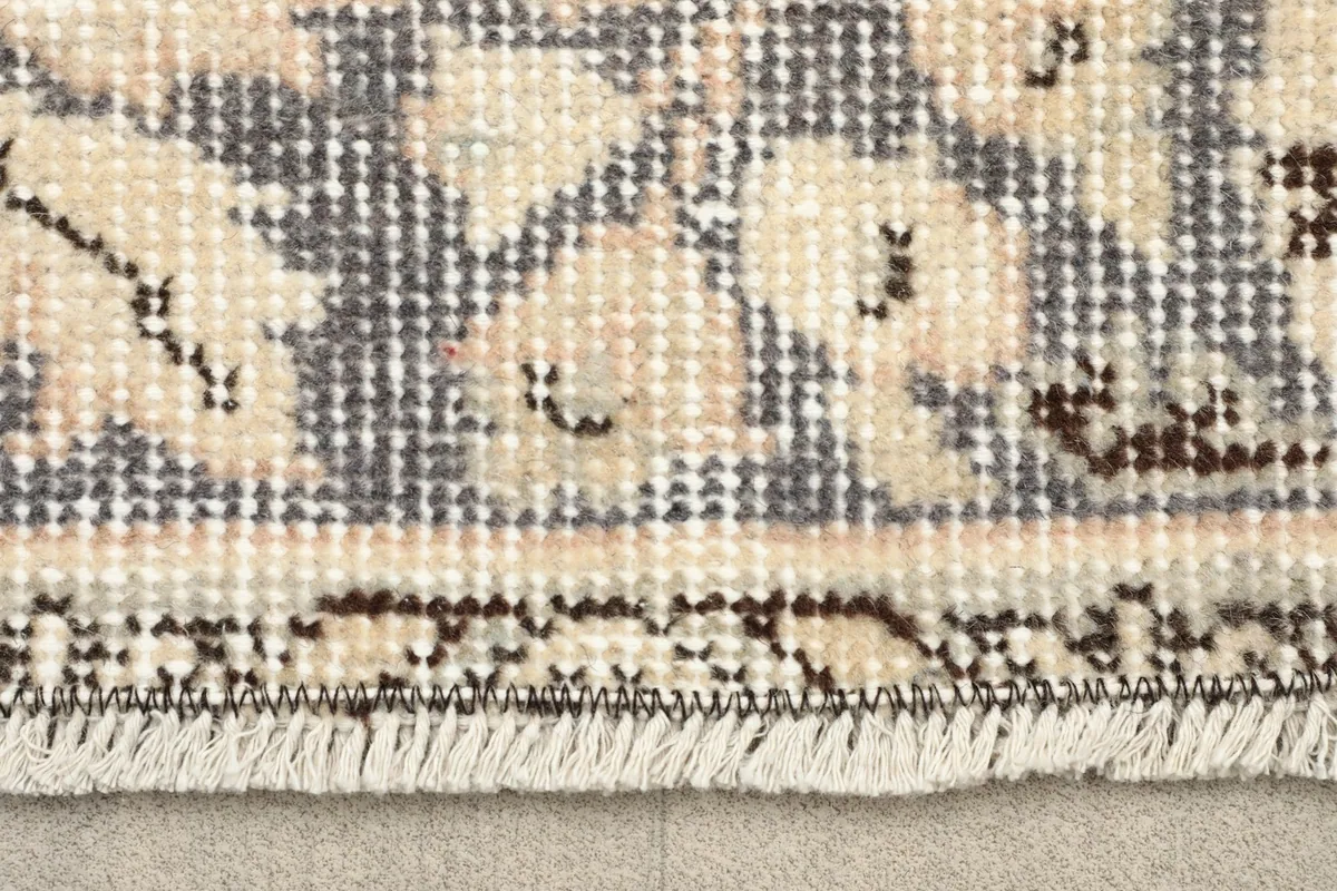 Close-up detail of the low wool pile and fringe of the vintage rug