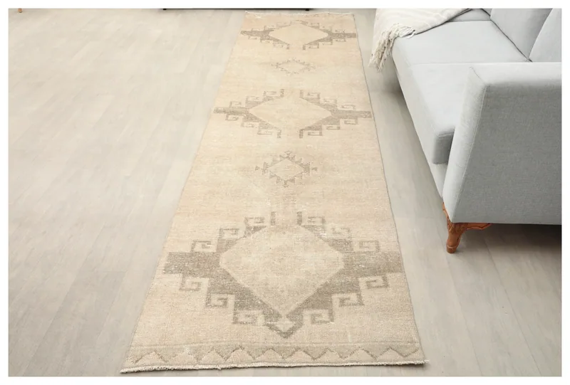 Full overhead view of the 2'11" x 11'1" ivory and gray vintage Anatolian runner on a white floor.