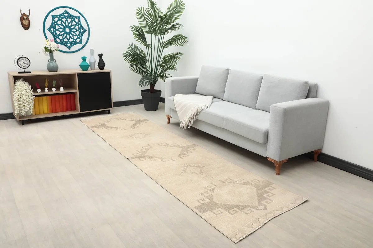 Vintage Anatolian runner rug laid in a modern living room setting next to a gray sofa.