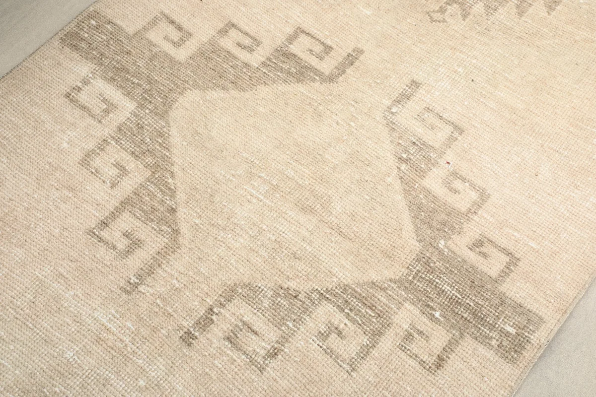 Close-up of the hand-knotted wool pile and a geometric design, showing variations in color and texture.