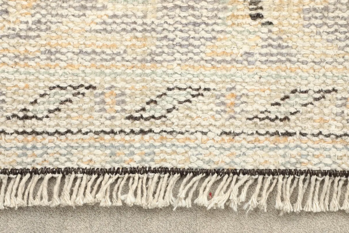 Close-up of the short fringe and the tightly woven edge of the vintage wool rug