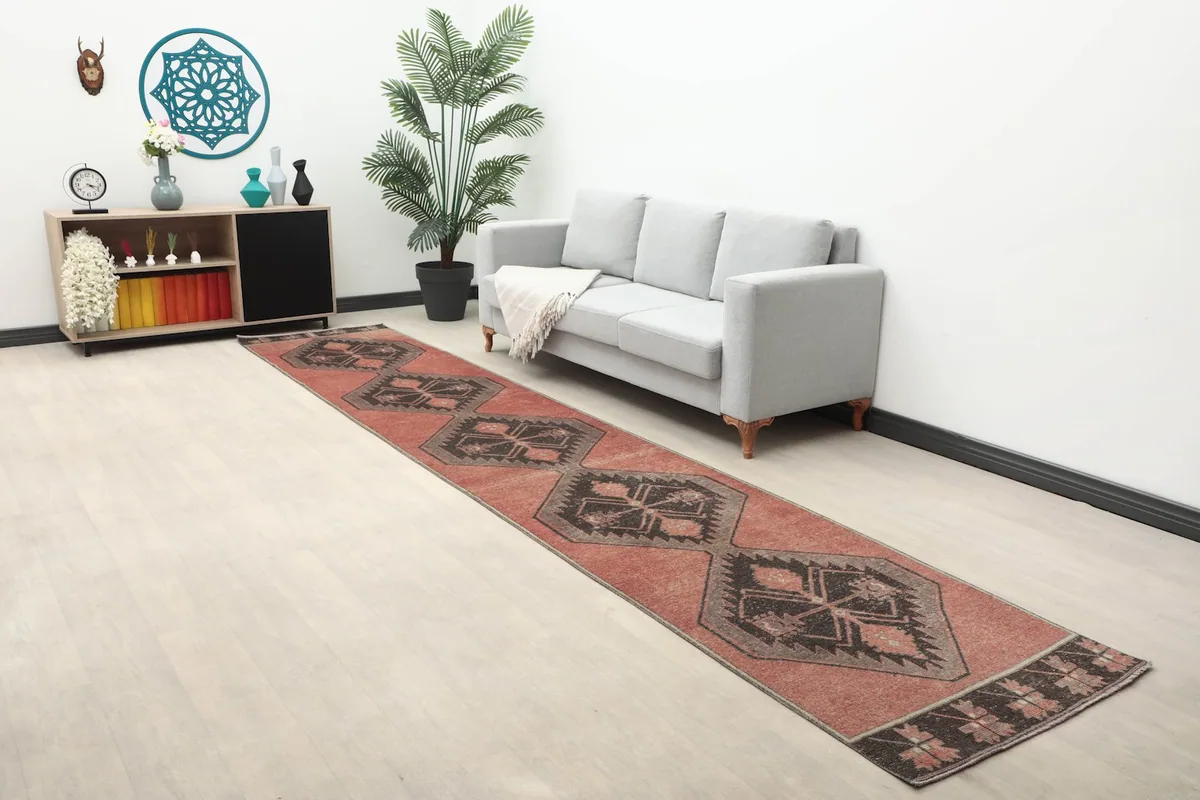 Wide angle view of the long rust runner rug stretching across a room with a sofa and decor.