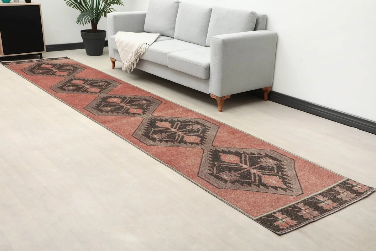 Close-up angle view of the rust runner rug in a room, showing its length and geometric design.